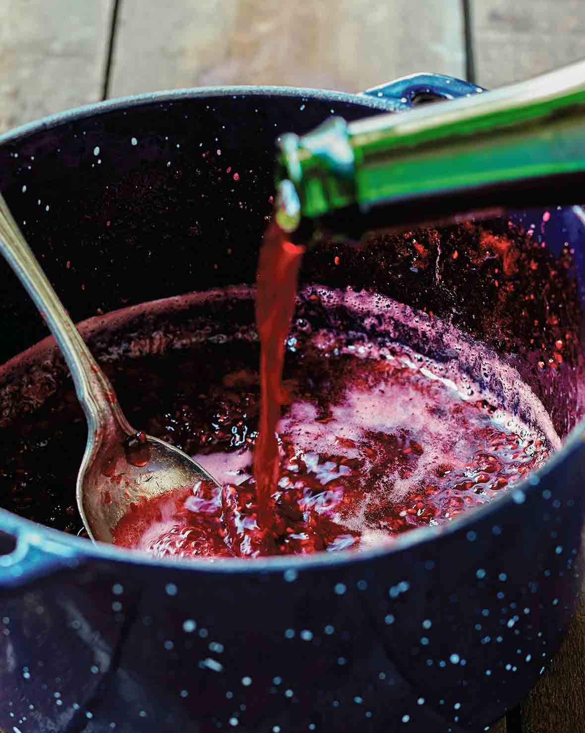 A pot of raspberry jam with framboise being added to it.