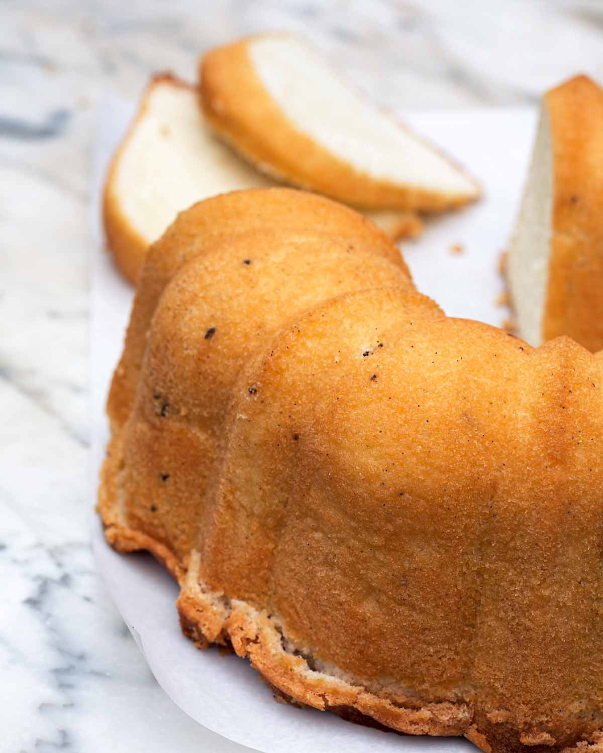 A vanilla pound cake, cut, on a marble slab