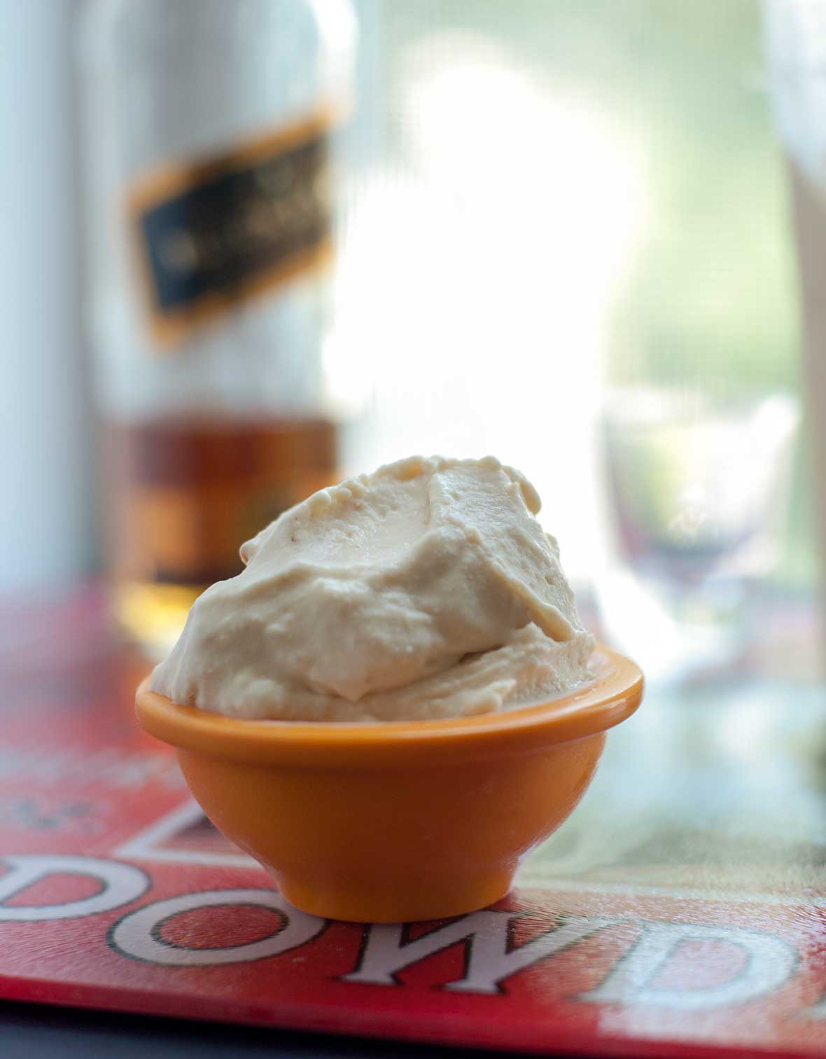 A small orange bowl filled with whiskey and fig gelato