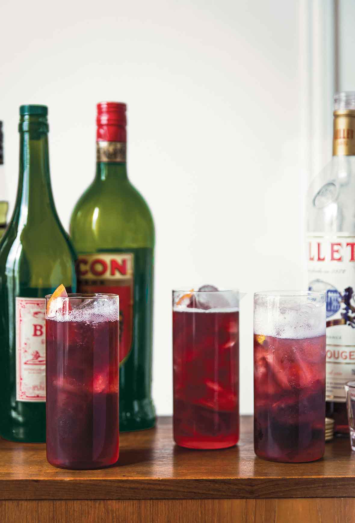 Three Collins glasses filled with Lillet tonic and topped with a grapefruit wedge.