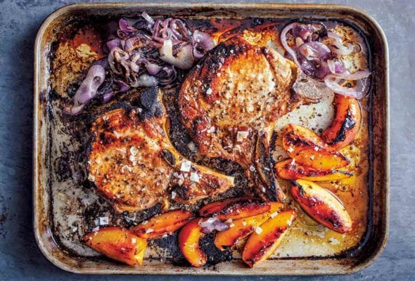 A rimmed sheet pan with roast pork with peaches and cooked red onion.