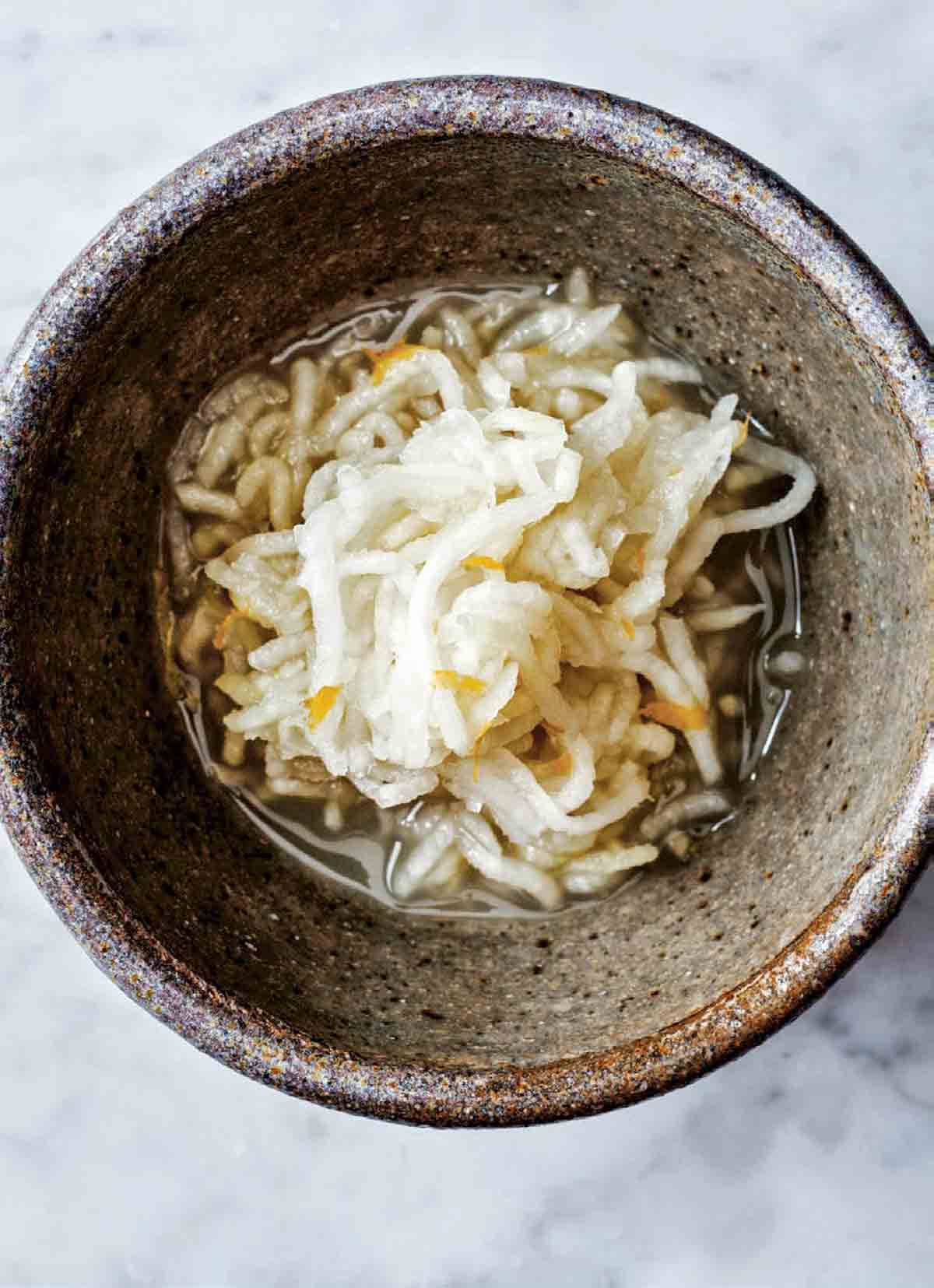 An earthenware bowl partially filled with kohlrabi kraut.