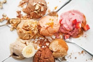 Seven scoops of vegan banana ice cream with some small spoons tucked underneath.