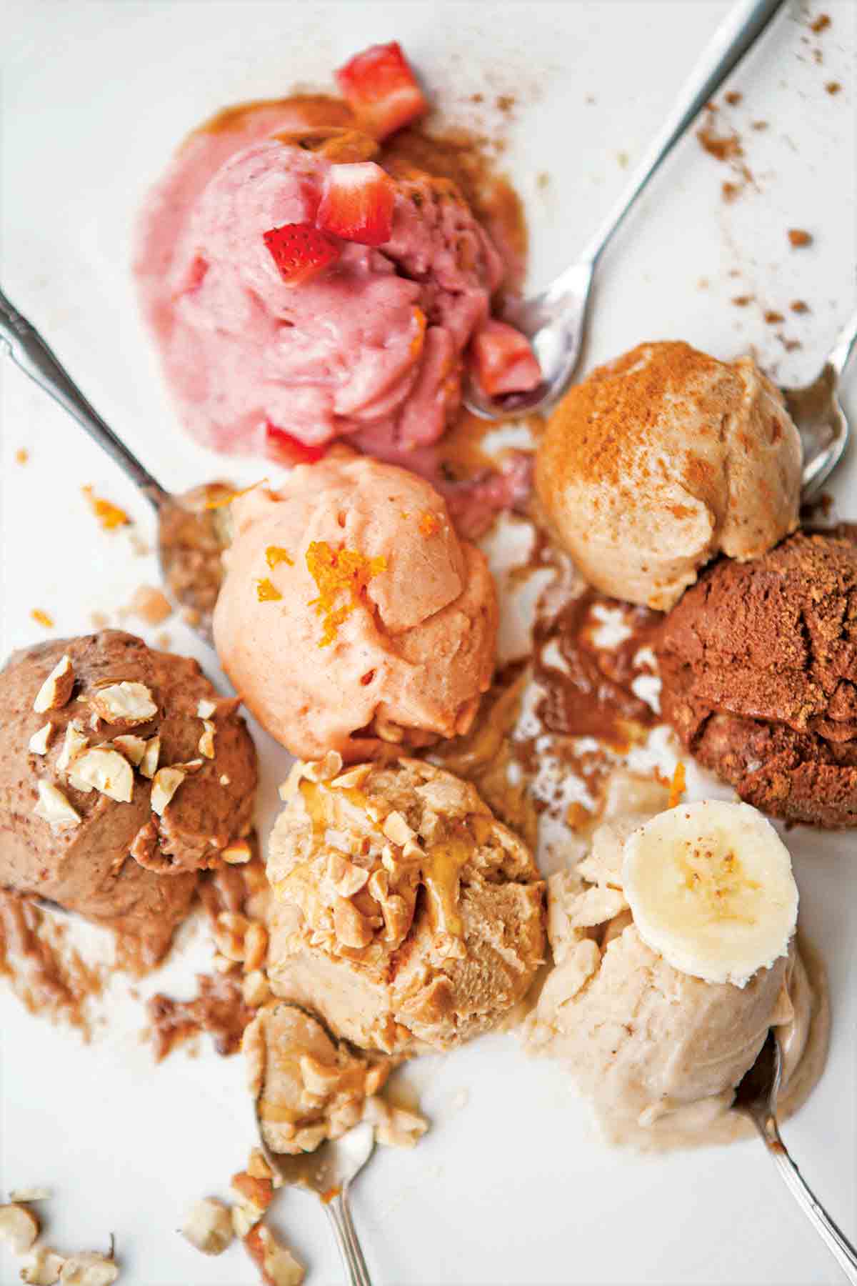 Seven scoops of vegan banana ice cream with some small spoons tucked underneath.