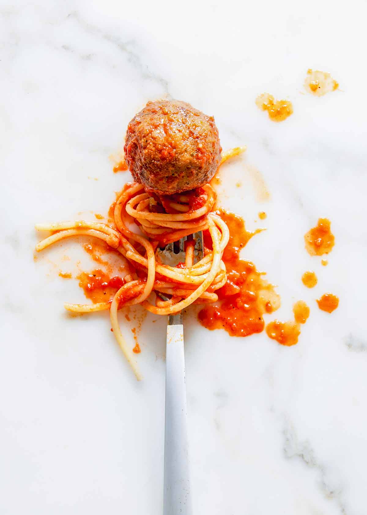 A single eggplant meatball on a fork with spaghetti and tomato sauce.