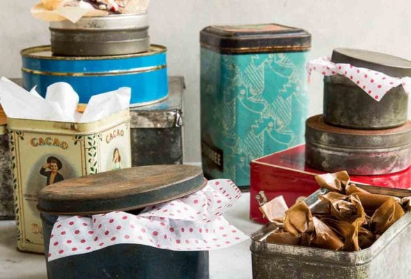 An assortment of holiday cookie tins with tissue paper sticking out of them..