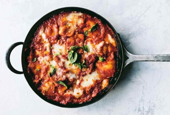 A metal skillet filled with easy skillet lasagna and garnished with basil leaves.