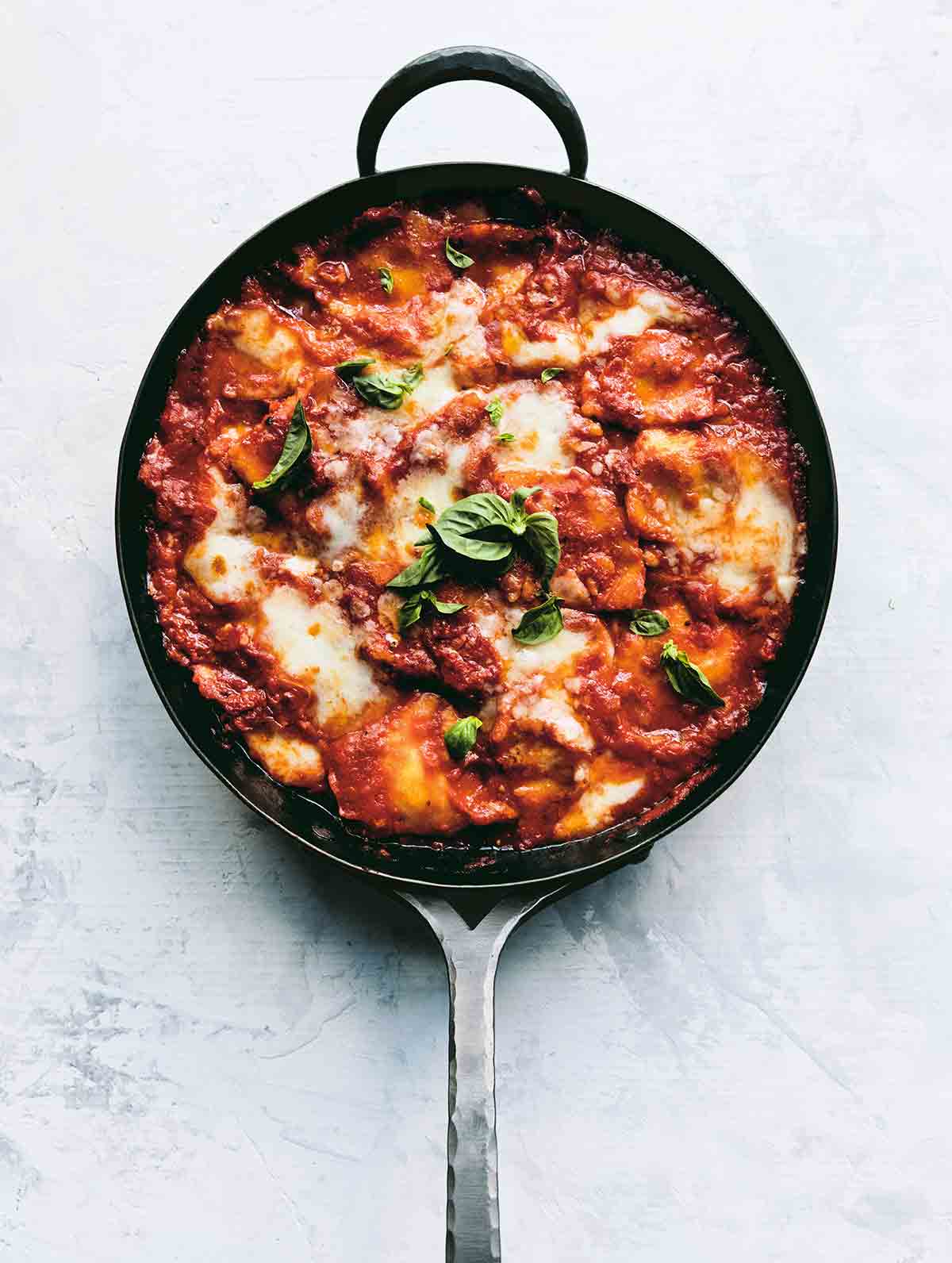 A metal skillet filled with easy skillet lasagna and garnished with basil leaves.