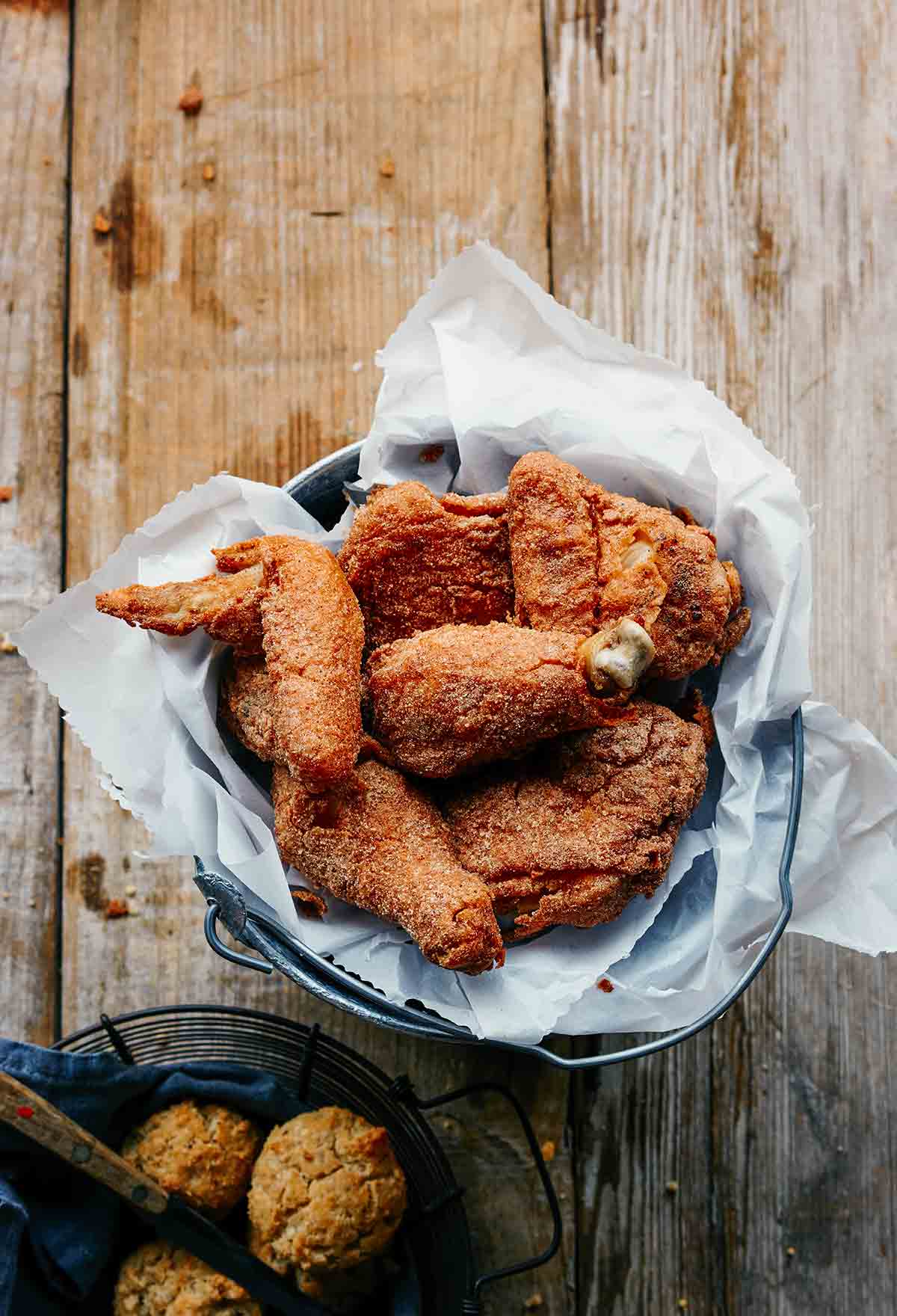Several pieces of gluten-free dairy-free fried chicken in a parchment-lined metal bucket.