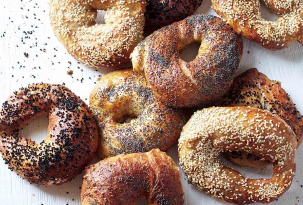 A variety of homemade bagels on a white surface.