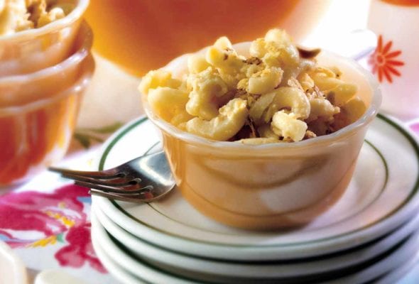 A small dish of not-from-a-box macaroni and cheese on a stack of plates with a fork resting beside it.