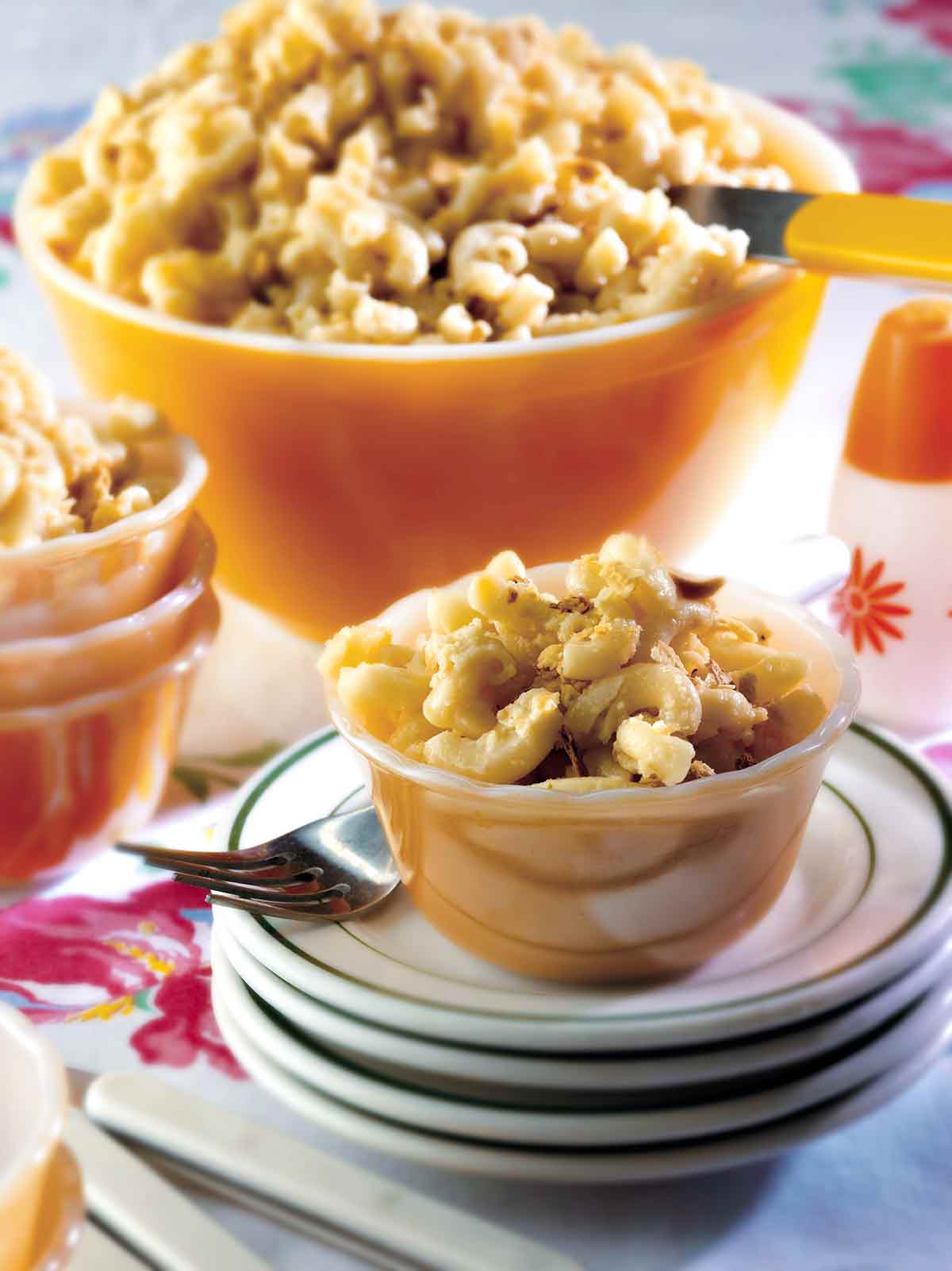 A small dish of not-from-a-box macaroni and cheese on a stack of plates with a fork resting beside it.
