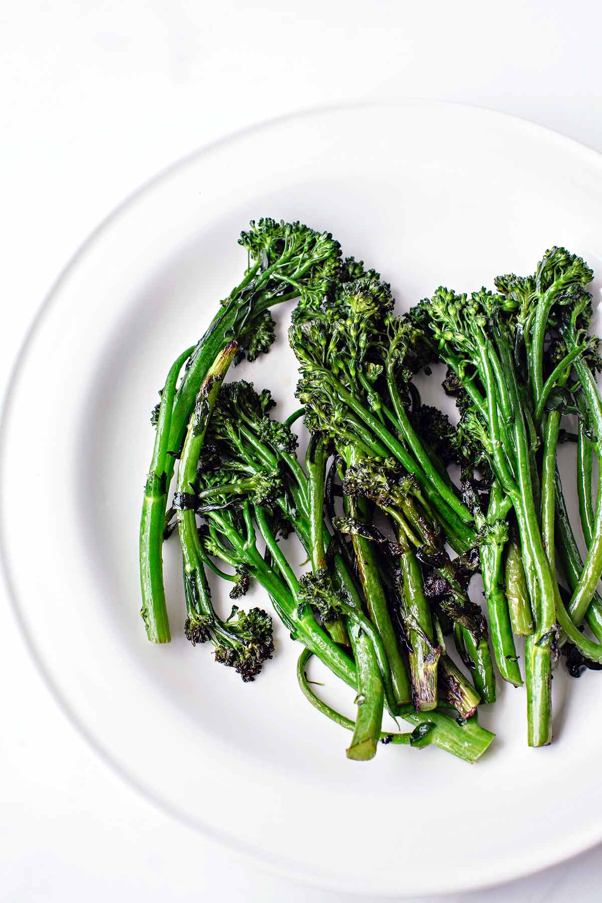 A white plate of skillet-charred broccolini.