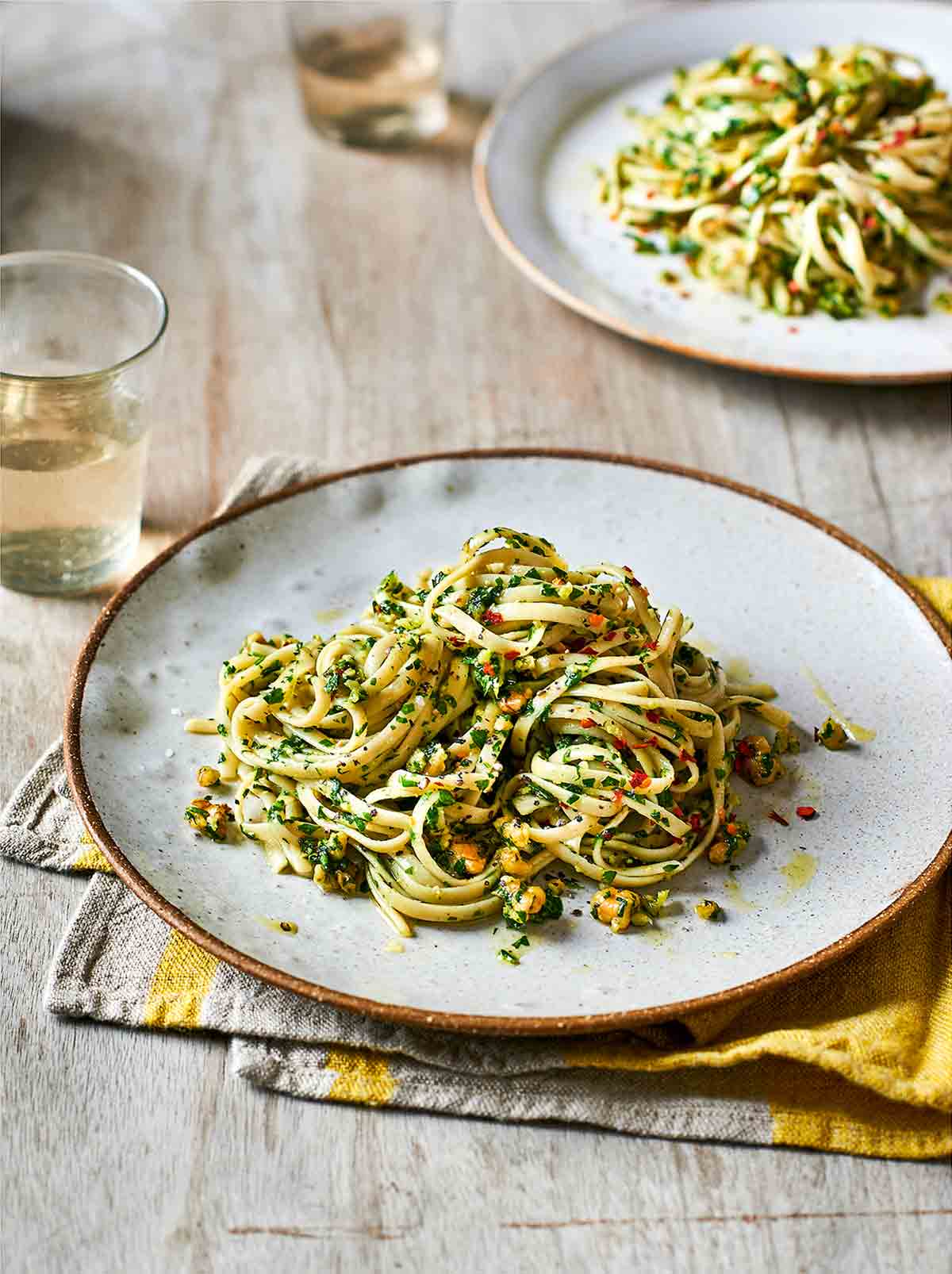 A gold-rimmed white plate topped with a serving of walnut parsley pesto pasta.