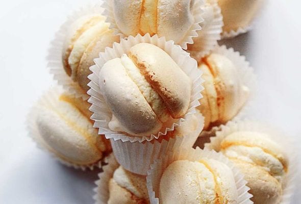 A pile of cream-filled macarons, each in a white wrapper.