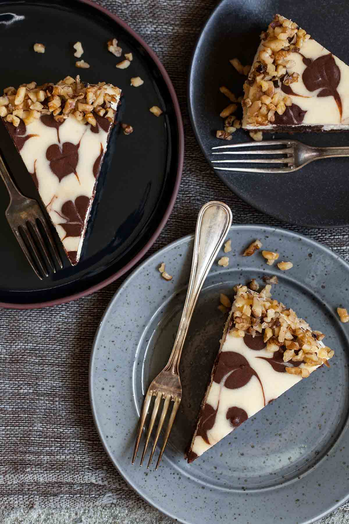 Three pieces of Junior's brownie swirl cheesecake on separate plates, each with a fork.