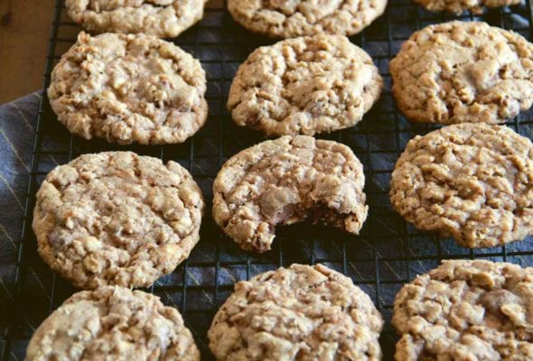 A batch of oatmeal chocolate chip cookies on a wire rack.