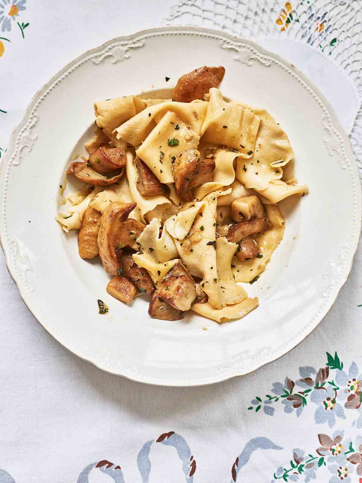 A white dinner plate filled with strapponi pasta with porcini mushrooms and mint.