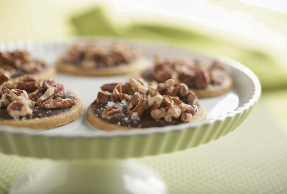 Five toffee cookies with dark chocolate glaze on a cake stand.