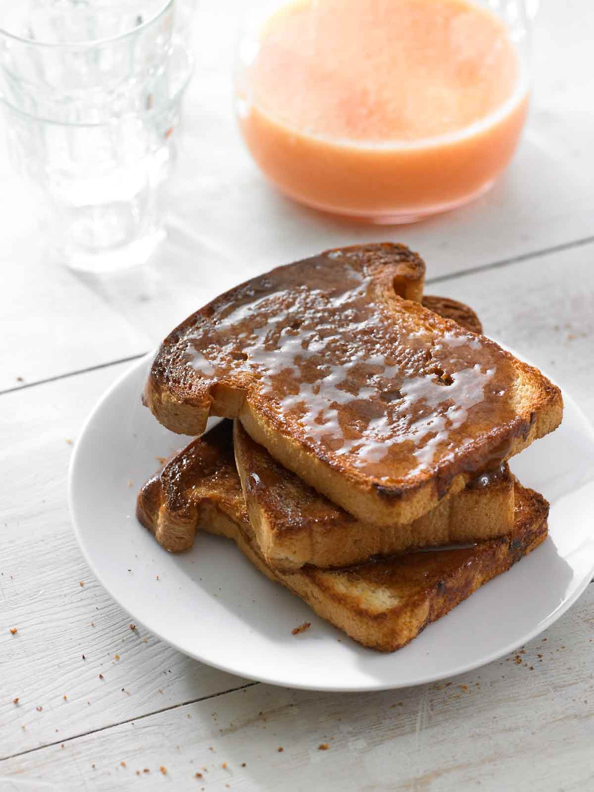 Three slices of cinnamon toast stacked on a white plate.