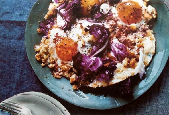 A blue plate topped with two fried eggs with crisp bread crumbs and radicchio.