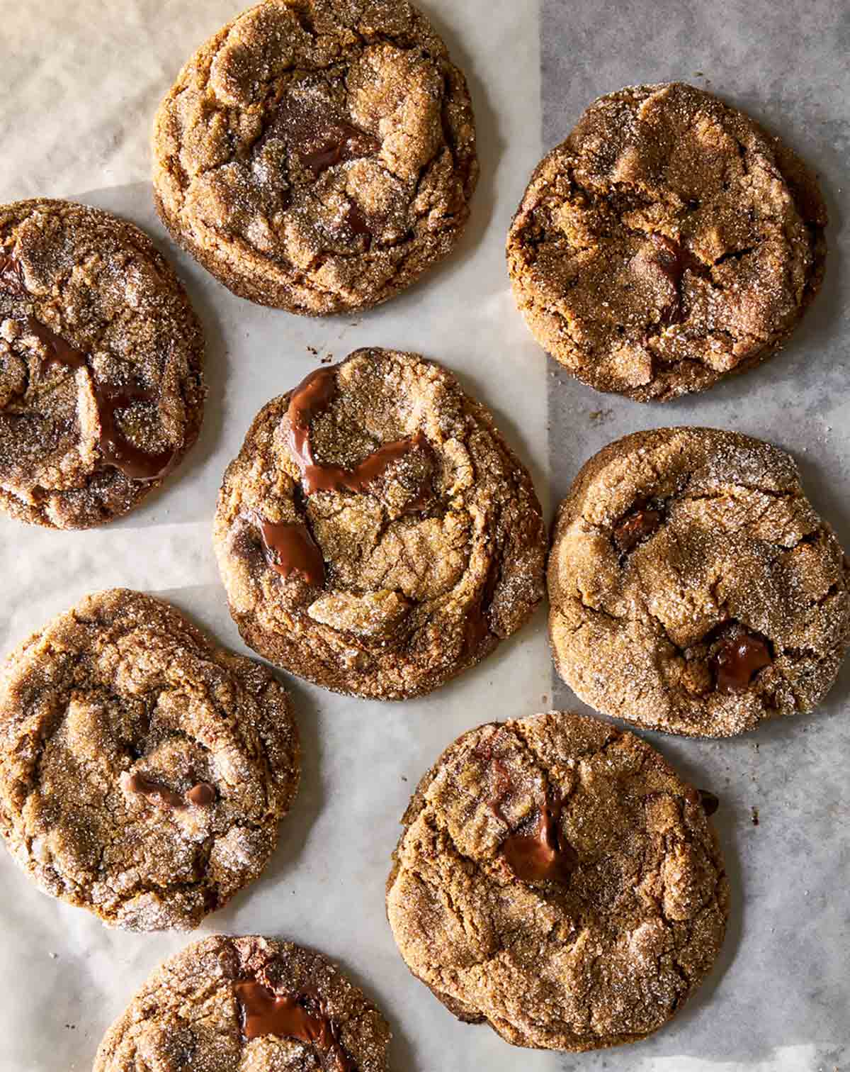 Several ginger chocolate chunk cookies on a piece of parchment paper.
