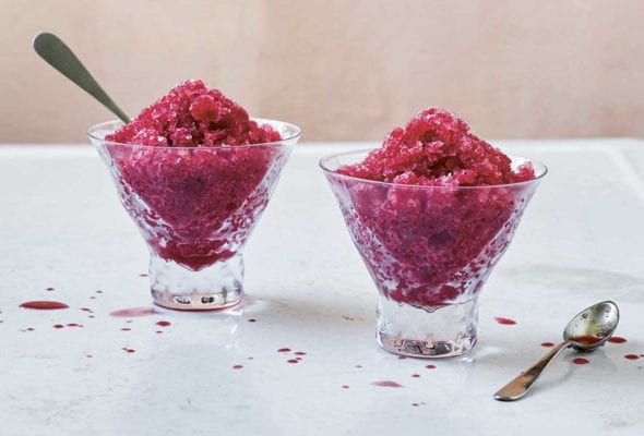 Two small glass dishes of blood orange granita, one with a spoon in it and the other with a spoon resting beside it.