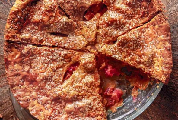 A rhubarb brown sugar pie cut into 7 wedges with one slice missing.