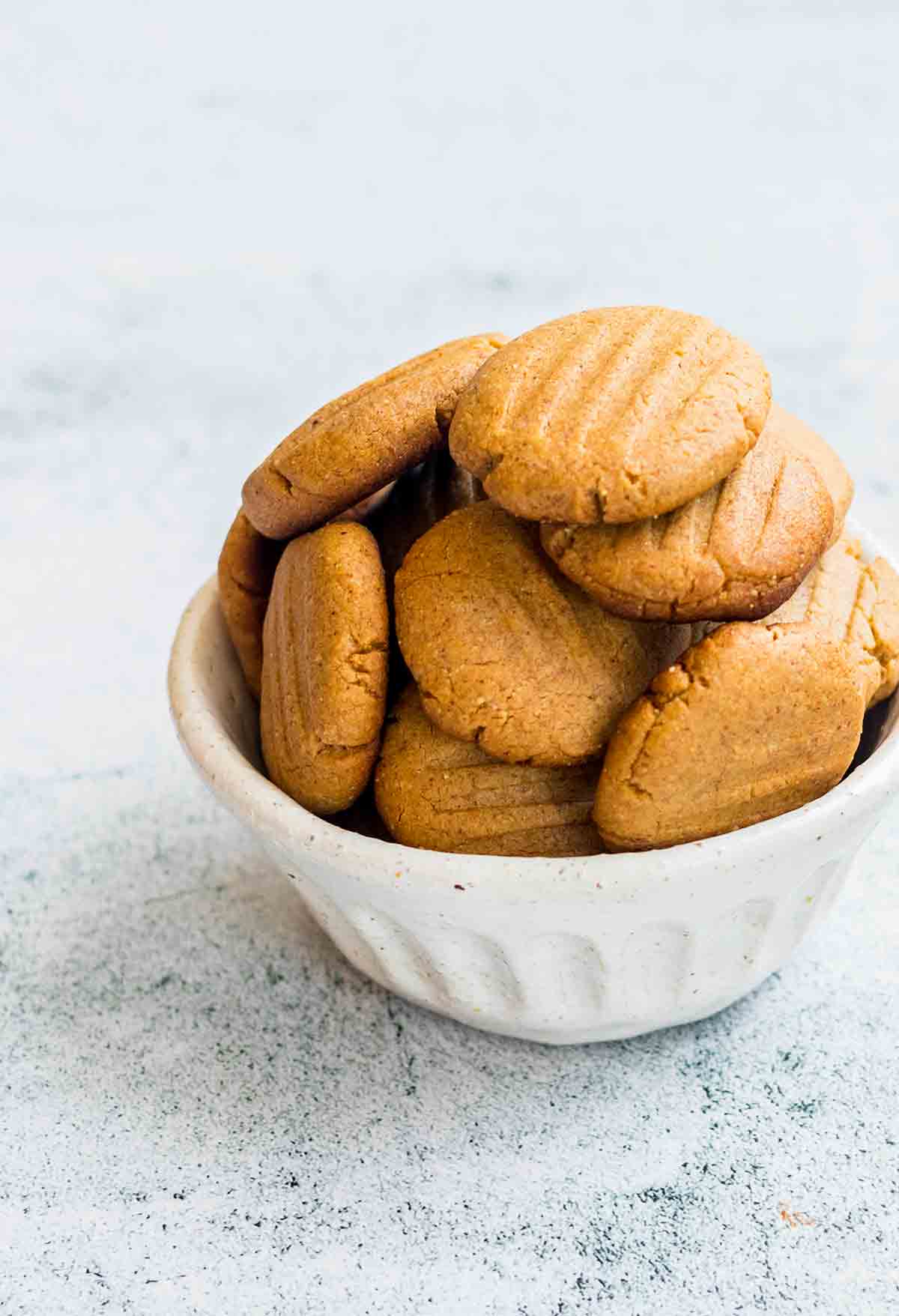 A white bowl filled with soft peanut butter cookies.