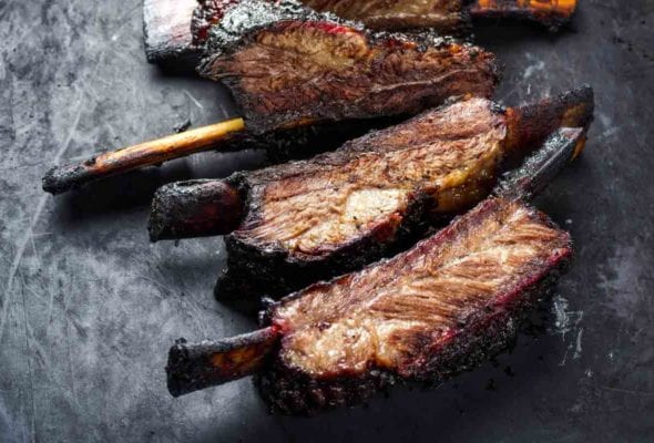 A slab of barbecued beef back ribs cut into individual ribs.