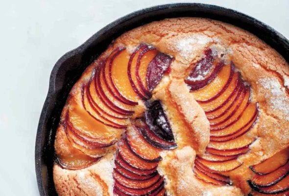A cast-iron skillet plum cake with slices of fanned out plums baked in