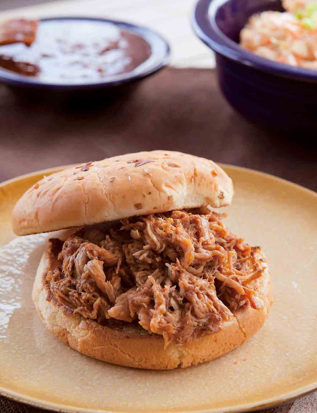 Slow cooker pulled pork piled on a bun on a plate.