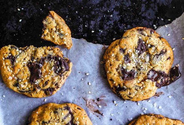A few tahini chocolate chip cookies on a torn piece of parchment paper.