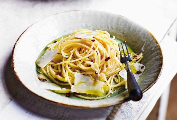 A bowl of spaghetti all'Aglio e Olio topped with olive oil and flakes of Parmesan cheese.