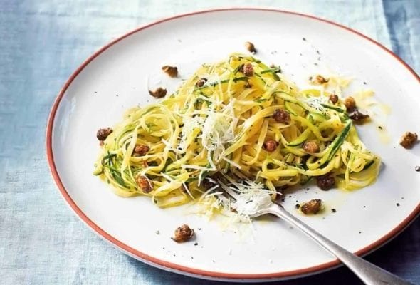 A white plate of zucchini linguine--with pasta, zucchini, garlic, capers, mint, dill, and cheese with a fork