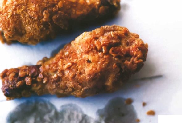 Three pieces of crispy fried chicken on grease-stained paper.