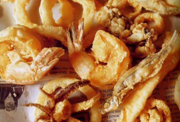 A pile of lightly fried shelfish - fritto misto amalfitano - on a piece of newspaper.