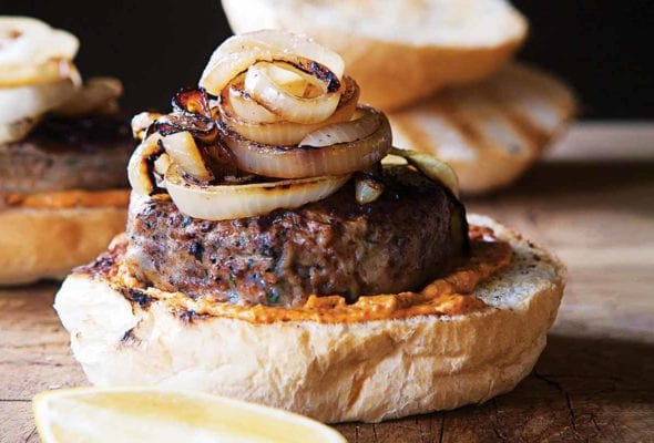 A lamb burger on half a bun topped with grilled Spanish onions.