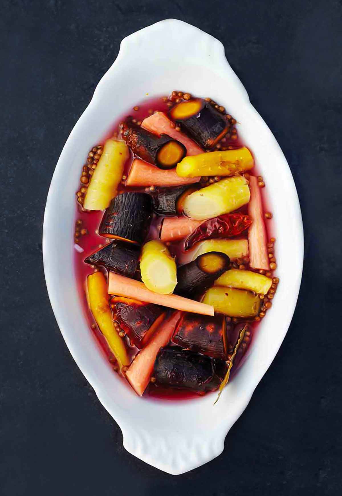 A white oval serving dish filled with pickled carrots.