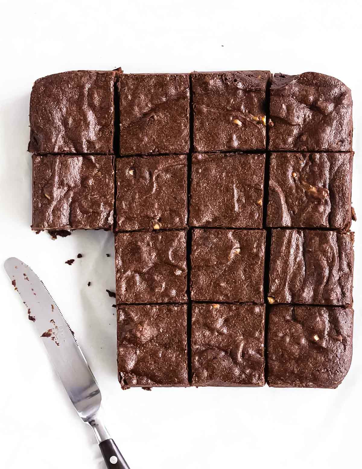 A batch of Rose Levy Beranbaum's fudge brownies cut into 16 squares, with two missing and a knife resting beside.