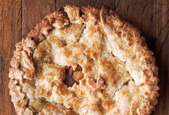 A baked hot buttered rum apple pie on a wooden board.
