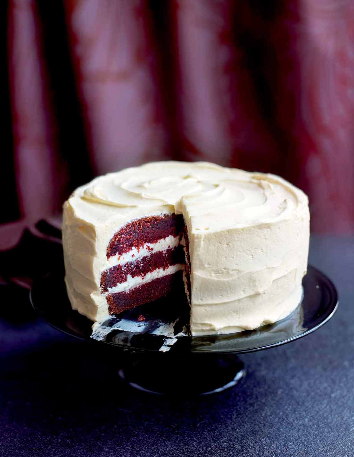 A red velvet cake with cream cheese frosting on a cake stand