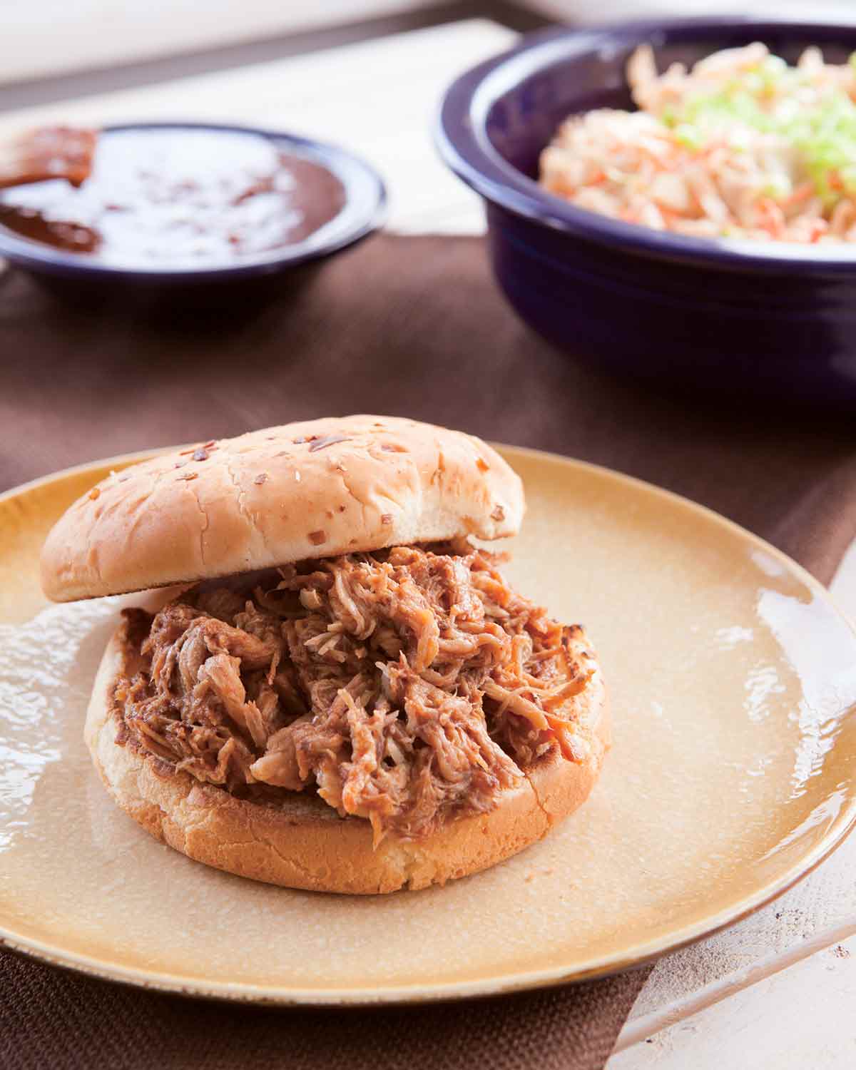 Slow cooker pulled pork piled on a bun on a plate.