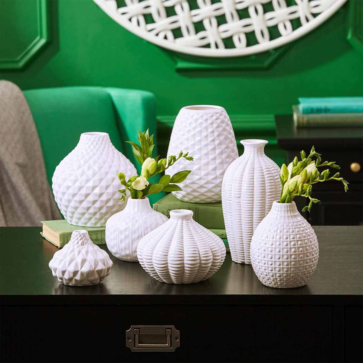 Artisan Carvings Set of 7 Vases with green wall behind them.