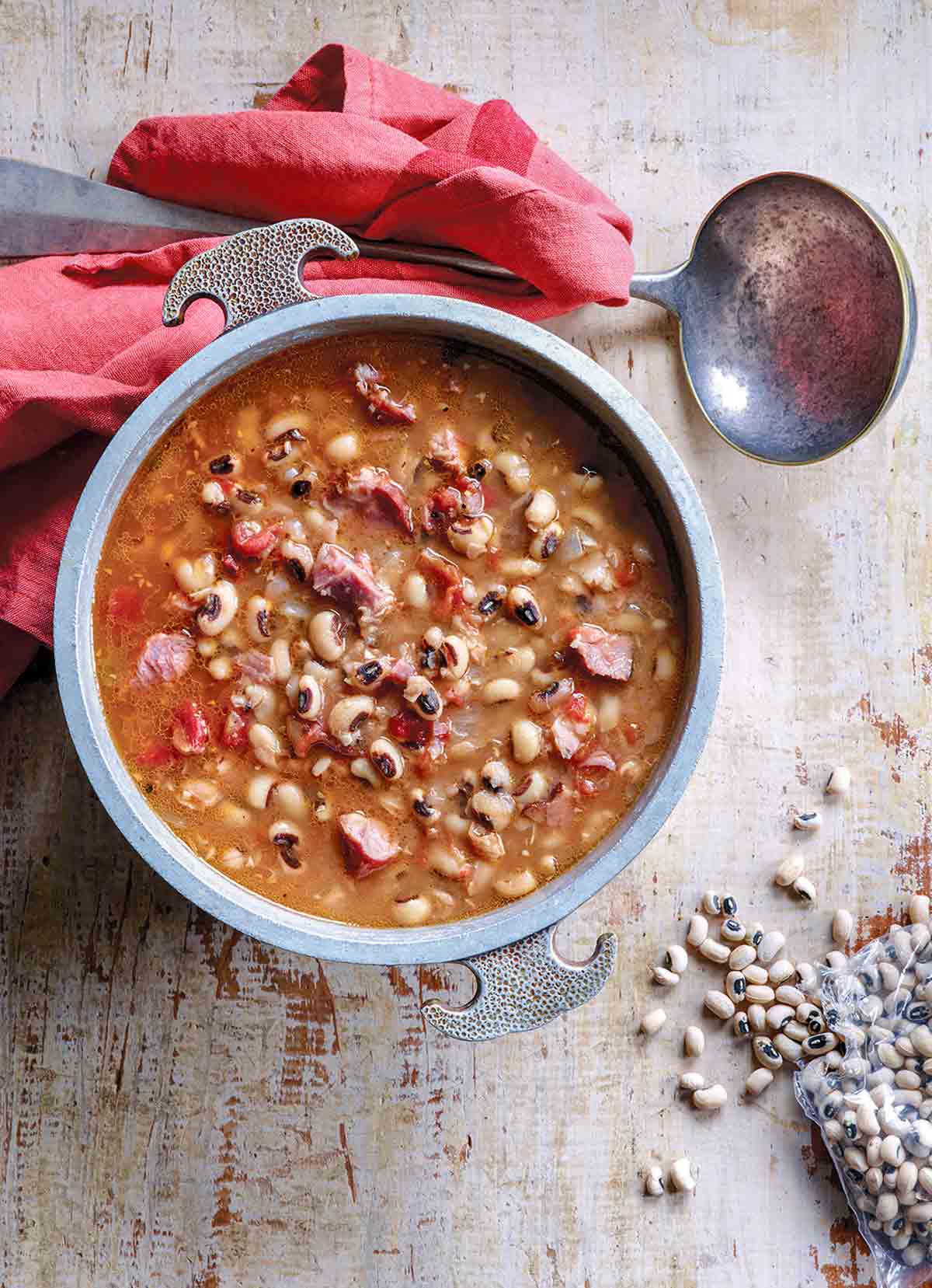 Bowl of black-eyed peas in a tomato broth on a sheet of wood