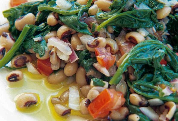A white plate with black-eyed peas, spinach, red onion, and red pepper