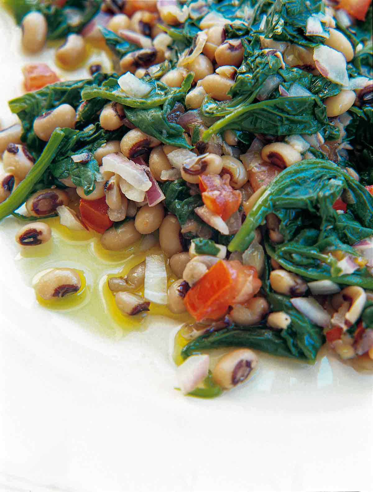 A white plate with black-eyed peas, spinach, red onion, and red pepper