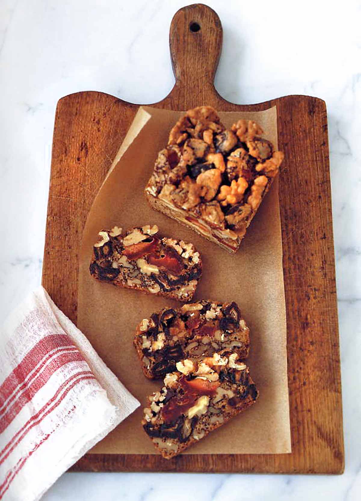 Dried fruit and nut cake cut into three slices on a cutting board on marble