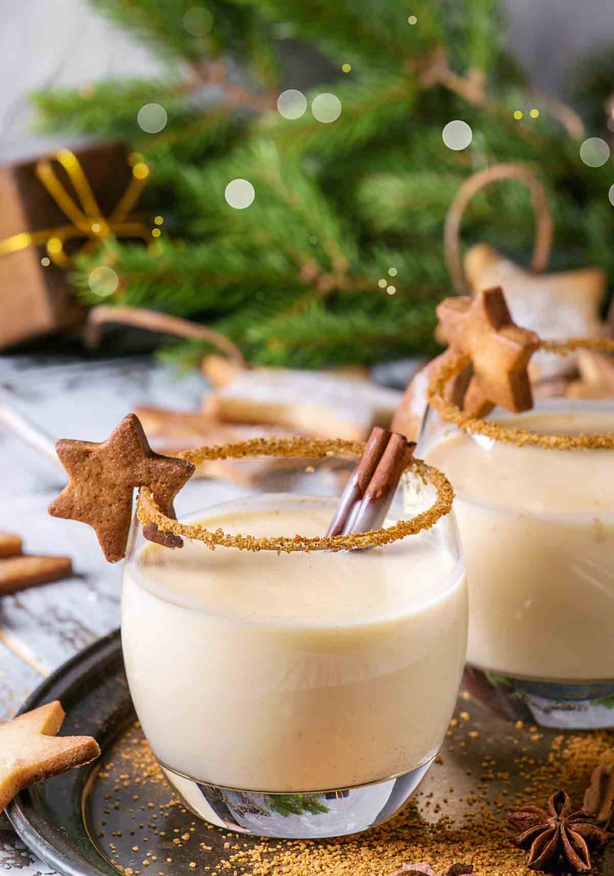 Two glasses filled with eggnog with a gingerbread star on the lip