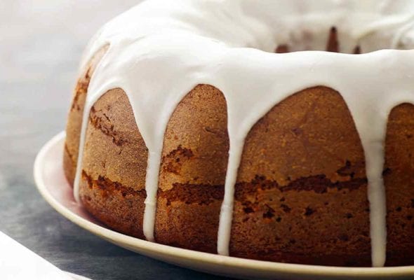 A glazed pumpkin pound cake on a plate--a pumpkin Bundt cake with a milk-sugar poured glaze